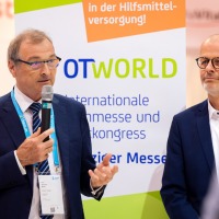 Zwei Männer stehen vor einem Roll-up-Display auf dem das Logo der OTWorld zu sehen ist.  Zwei Männer stehen vor einem Roll-up-Display auf dem das Logo der OTWorld zu sehen ist.