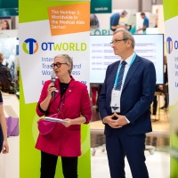 Vier Personen bei einer offiziellen Ansprache auf der OTWorld, eine Frau mit Mikrofon spricht, daneben zwei Männer im Anzug und eine junge Frau mit Prothese. Vier Personen bei einer offiziellen Ansprache auf der OTWorld, eine Frau mit Mikrofon spricht, daneben zwei Männer im Anzug und eine junge Frau mit Prothese.