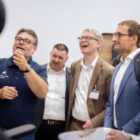 Gruppe von Fachbesuchern auf der OTWorld betrachtet mit Begeisterung eine Produktvorführung, mehrere Personen lachen und unterhalten sich angeregt. Gruppe von Fachbesuchern auf der OTWorld betrachtet mit Begeisterung eine Produktvorführung, mehrere Personen lachen und unterhalten sich angeregt.