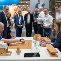 Zwei Personen demonstrieren auf der Reha- und Therapiegeräte an einem Tisch, umgeben von einer Gruppe interessierter Messebesucher in Businesskleidung. Zwei Personen demonstrieren auf der Reha- und Therapiegeräte an einem Tisch, umgeben von einer Gruppe interessierter Messebesucher in Businesskleidung.