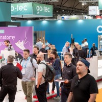 Besucherinnen und Besucher schlendern über die OTWorld vorbei am farbenfrohen Stand von go-tec, während sich andere an den Stationen informieren Besucherinnen und Besucher schlendern über die OTWorld vorbei am farbenfrohen Stand von go-tec, während sich andere an den Stationen informieren